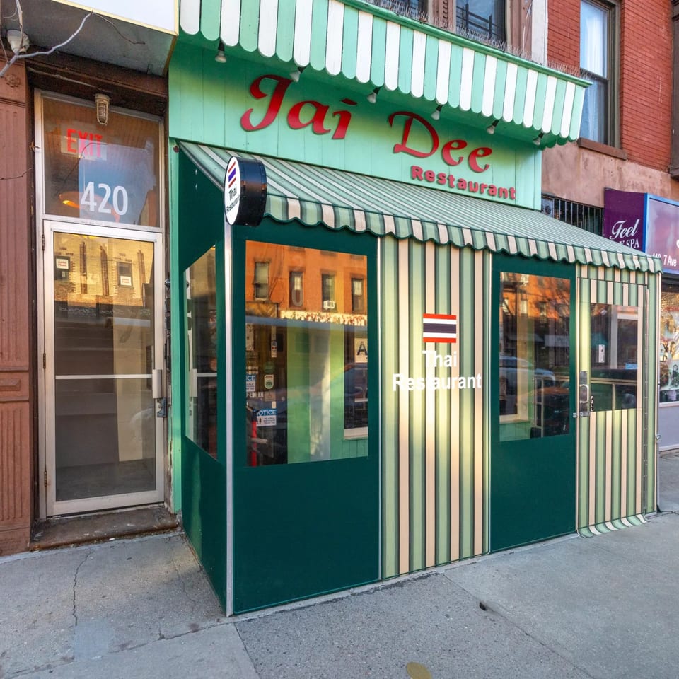 The exterior of Jai Dee Thai Restaurant, featuring a green and white striped awning and outdoor dining structure.