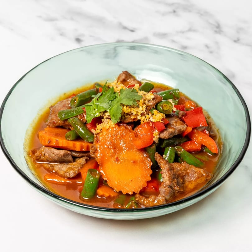 Thai beef stir-fry with carrots, green beans, and red peppers in a rich sauce.